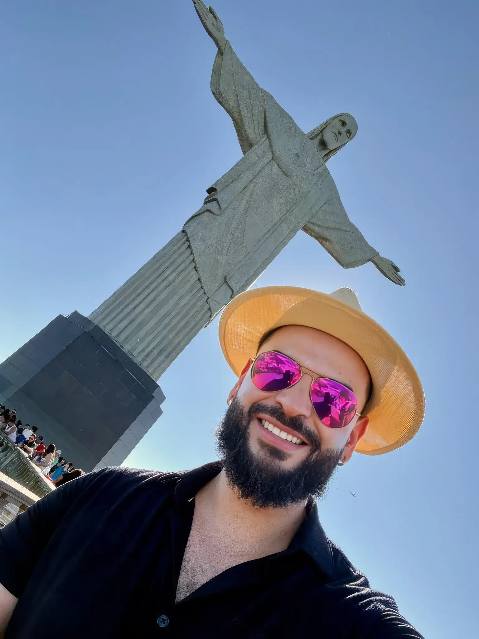 Johnson smiling in a straw hat and sunglasses below the Christ the Redeemer statue in Rio de Janeiro
