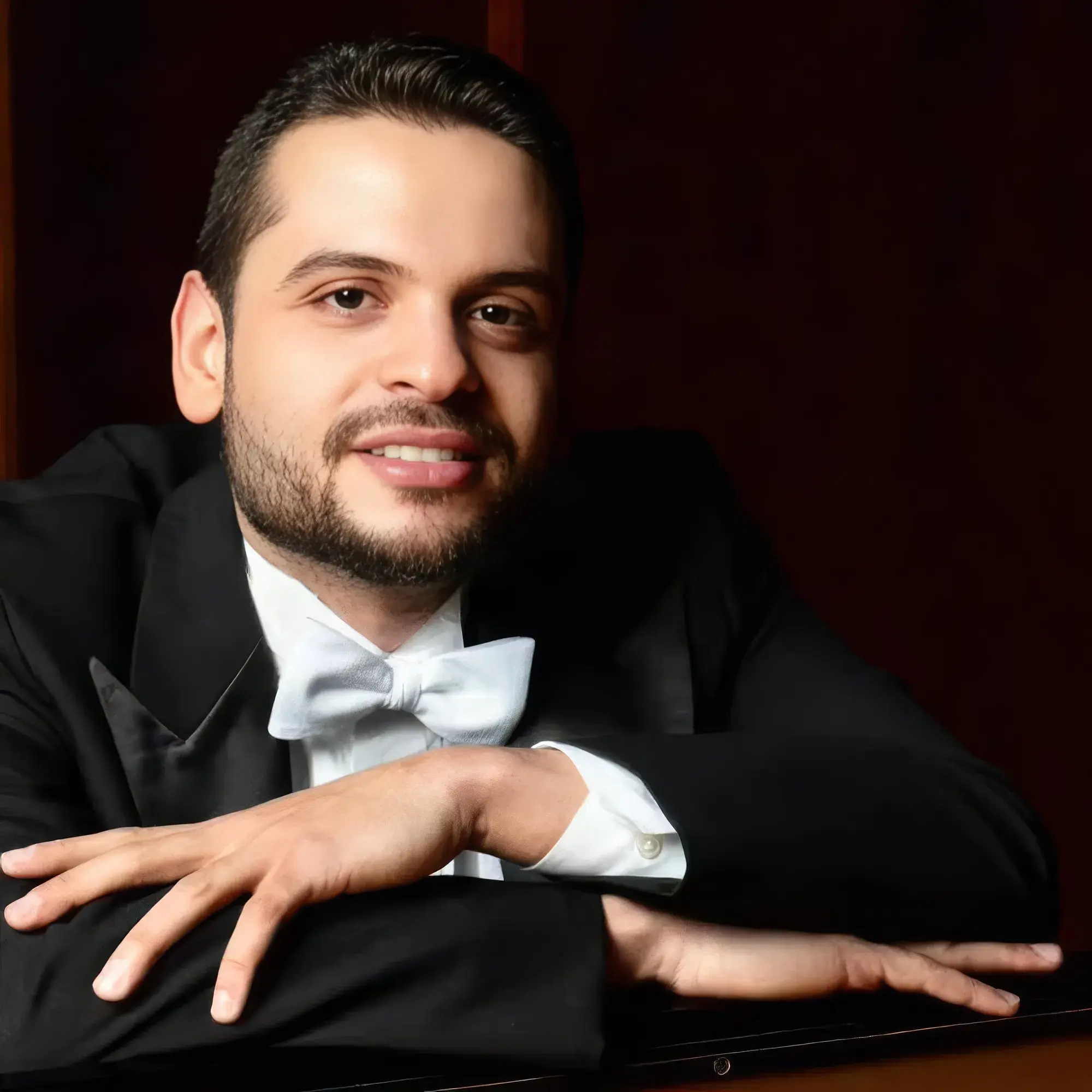 Portrait of Johnson Gouvêa in white tie, leaning on a grand piano